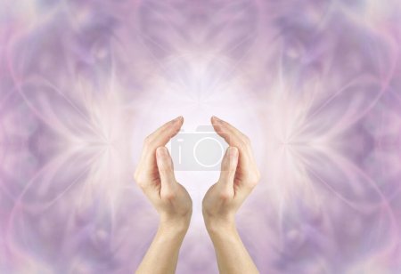 Healer Connecting to Divine Intelligence channeling high resonance Healing Energy - female cupped hands with light between against an ethereal lilac  background with space for messages
