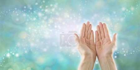 Téléchargez les photos : Reiki Healer canalisant l'énergie de guérison à haute résonance - mains ouvertes féminines sur un fond vert pastel effet bokeh pétillant avec de l'espace pour les messages ou modèle de carte de visite - en image libre de droit