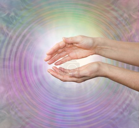 Photo for Reiki Master working with healing vibes - female cupped hands sending out healing frequency intention against a subtle pastel  coloured resonating ethereal background and copy space - Royalty Free Image