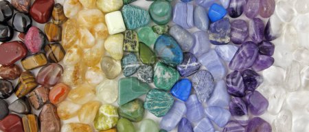 Photo for Chakra Crystal Healing wide Background template - Rows of tumbled polished healing crystal laid out in chakra colours white, purple, blue, green, yellow, orange, red ideal for crystal healing theme - Royalty Free Image