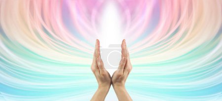 Colour energy healing background - hands making a v shape with white light between against a flowing ethereal multicoloured background with copy space all around