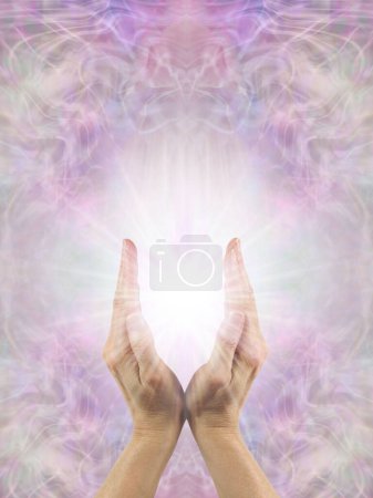 Reiki Healer using the Power of Intention to send healing energy - Female hands with white starlight  between against a beautiful pink and spiritual ethereal background with space for text