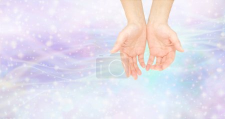 Humble healing hands message background - female cupped hands with beautiful gentle wispy energy field around and shimmering glittering stars with copy space for spiritual message 