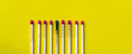 Success, defeat, achievement. The concept of happiness. Matches on yellow background. Burnt dark match among normal matches. Burning match fire to its neighbors, a metaphor for ideas and inspiration