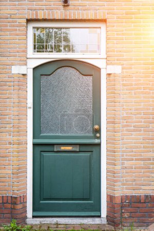 Facade of typical Dutch door house with brick walls, steps, front door windows. Doors on the street, Netherlands