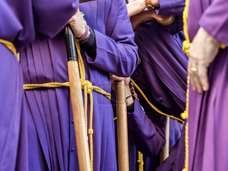 Photo for People in purple robes and yellow belts, holding wooden staffs during a procession. Selective Focus. - Royalty Free Image