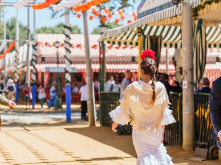 Seville, Spain - April 26, 2023 : Woman in white flamenco dress at the festive Seville Fair.