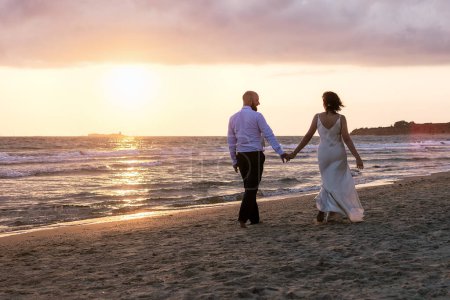 A couple enjoys a serene walk on the beach at sunset.