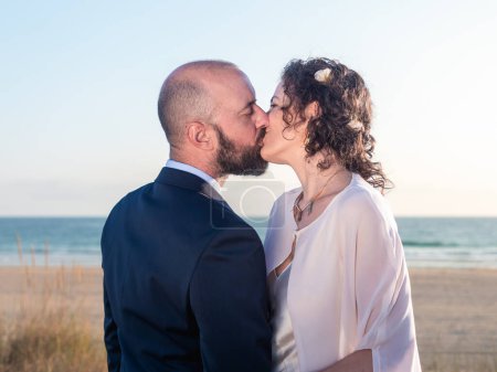Téléchargez les photos : Couple romantique donnant sur l'océan au coucher du soleil - en image libre de droit