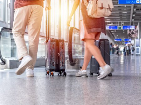 Unscharfes Foto von Unbekannten, die mit Koffer im Flughafenterminal spazieren