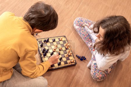 Deux enfants profondément concentrés sur le jeu d'échecs, assis par terre.