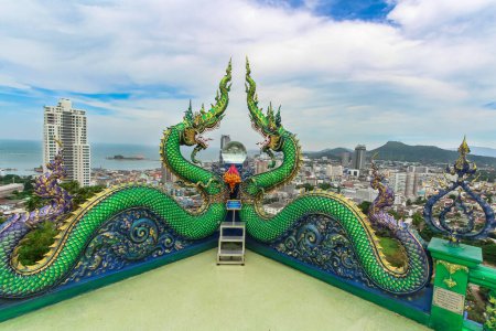 Green Serpent Dragons, Crystal Ball, and the majestic cityscape backdrop at Si Racha Temple, Chonburi.