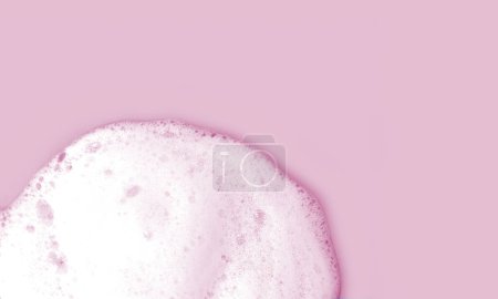 Skin care cleanser mousse foam texture. Soap, shower gel or shampoo foam bubbles on light pink background