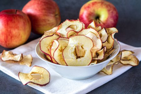 Téléchargez les photos : Croustilles de pommes séchées bio faites maison dans un bol. Concept de collations santé - en image libre de droit