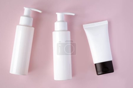 Téléchargez les photos : Bouteilles blanches et tube de produits cosmétiques avec maquette de marque sur fond rose. Soin de la peau et concept beauté - en image libre de droit