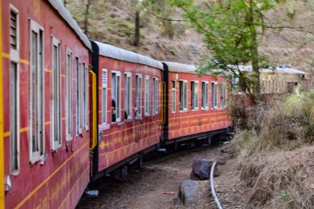 Foto de Toy Train moving on mountain slopes, beautiful view, one side mountain, one side valley moving on railway to the hill, among green natural forest. Toy train from Kalka to Shimla in India, Indian Train - Imagen libre de derechos