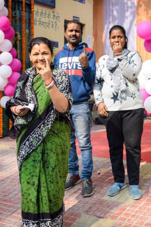 Foto de New Delhi, India - December 04 2022 - Unidentified people showing their ink-marked fingers after casting votes in front of polling booth of east Delhi area for MCD local body Elections 2022 - Imagen libre de derechos