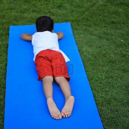 Photo for Asian smart kid doing yoga pose in the society park outdoor, Children's yoga pose. The little boy doing Yoga exercise - Royalty Free Image