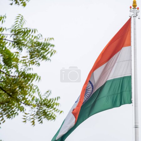 Photo for India flag flying high at Connaught Place with pride in blue sky, India flag fluttering, Indian Flag on Independence Day and Republic Day of India, tilt up shot, Waving Indian flag, Har Ghar Tiranga - Royalty Free Image