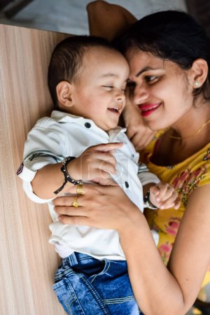 Photo for Loving mom carrying of her baby at home balcony. Bright portrait of happy mum holding child in her hands. Mother with her little 1 year old son. - Royalty Free Image