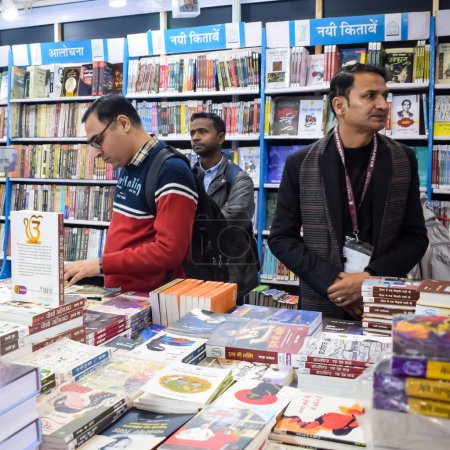 Téléchargez les photos : Delhi, Inde, 17 février 2024 - Diverses personnes du groupe d'âge lisant divers livres sur étagère à l'intérieur d'une librairie à Delhi International Book Fair, Books in Annual Book Fair au complexe Bharat Mandapam - en image libre de droit