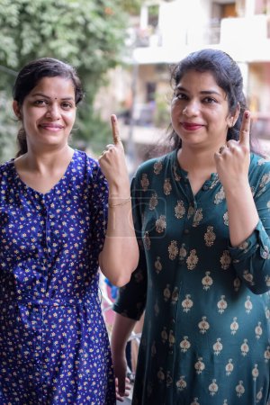 Two Smart young lady showing her ink-marked fingers after casting votes in front of polling booth of east Delhi area for general Lok Sabha Elections 2024