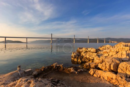 Photo for Bridge over the sea to the island of Peljesac in Croatia. Calm sea level with a beautiful white bridge in the foreground white stones. - Royalty Free Image