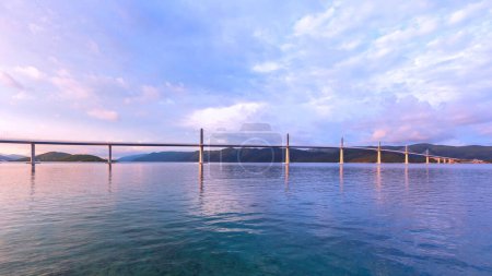 Photo for Beautiful modern bridge over the sea on Peljesac in Croatia. In the foreground houses and in the background the Peljesac mountain - Royalty Free Image