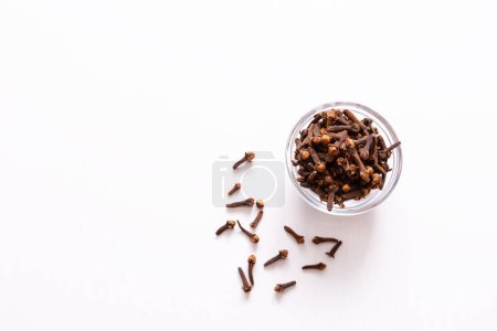 Photo for Clove spice, a small bowl of cloves in a small glass bowl on a white table - Royalty Free Image