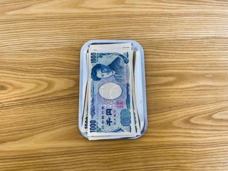 Tokyo, Japon - 24 février 2024 : Plusieurs billets de 1000 yens placés dans un bac à langer sur un plancher de bois.
