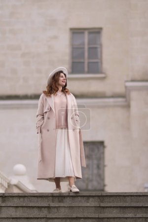 Photo for Woman in elegant coat and hat against an intricate architectural backdrop, harmoniously blending modern fashion with historical allure. The soft daylight adds to its timeless appeal - Royalty Free Image