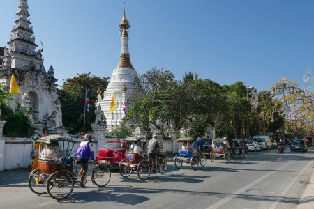 Foto de CHIANGMAI, TAILANDIA - 24 de diciembre: Triciclo taxi en la calle Tha Phae para los clientes que visitan Chiang Mai, Tailandia.Triciclo taxi en bicicleta es uno de los transportes públicos en Tailandia. - Imagen libre de derechos