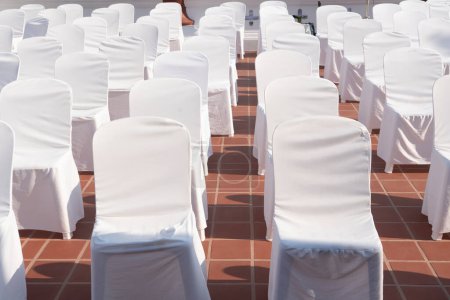Many  chairs with white elegant covers 