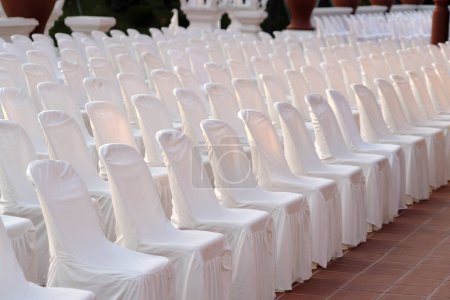 Many  chairs with white elegant covers 
