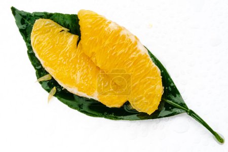 Téléchargez les photos : Peeled orange fruit pulp on green leaf isolated on white background. Macro photo of citrus fruit slice. Fresh, juicy pulp of orange - en image libre de droit