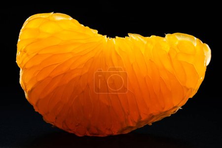 Téléchargez les photos : Tangerine pulp close up on black background. Peeled mandarin slice macro photo. Citrus fruit flesh texture. Clementine slice isolated on black background - en image libre de droit