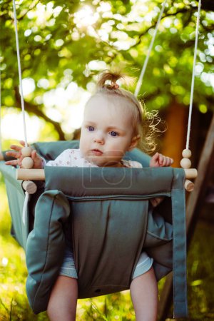 Téléchargez les photos : Jolie petite fille dans le swing. Balançoire bébé sur l'arbre dans le jardin. Enfant jouant dans la cour arrière - en image libre de droit