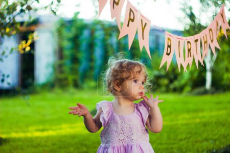 Téléchargez les photos : Jolie petite fille en robe. Célébration d'anniversaire dehors dans la cour. Une grande fête de jardin. Fête d'anniversaire. - en image libre de droit