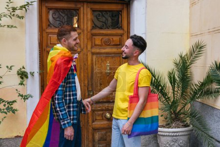 Foto de Una vibrante instantánea captura a dos amigos gays que exudan felicidad mientras se toman de la mano, su hogar adornado con símbolos LGBT coloridos. - Imagen libre de derechos