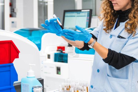 Técnico de laboratorio inspecciona una muestra de sangre en un laboratorio clínico con maquinaria de diagnóstico avanzada para pruebas