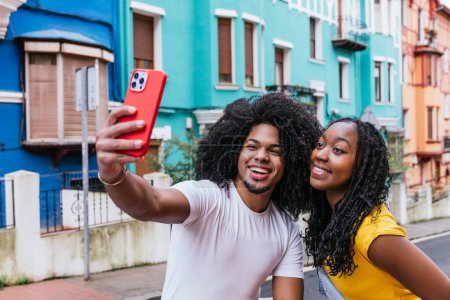 Friends making memories with a vibrant selfie in a lively urban neighborhood.