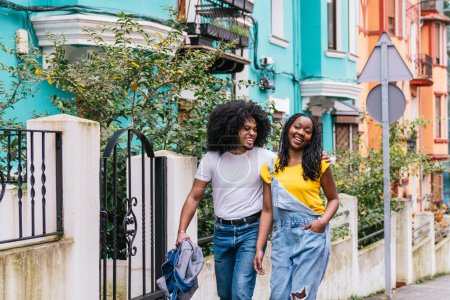 Latino friends enjoying a leisurely walk in a vibrant neighborhood, showcasing their joy and stylish urban wear.