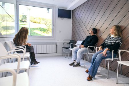 Patients calmly waiting in a bright, contemporary hospital waiting room with large windows.
