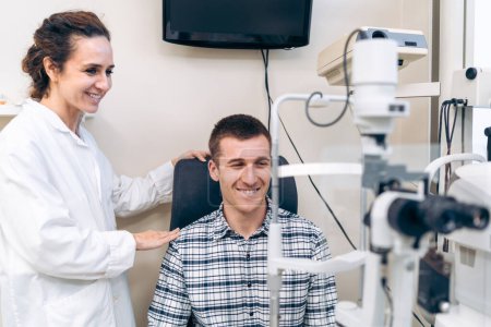 Téléchargez les photos : Heureux patient masculin en consultation avec une ophtalmologiste féminine - en image libre de droit