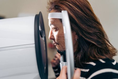 Focused retinal examination of a woman's eye with a diagnostic machine.