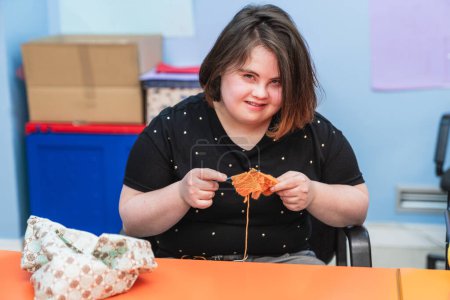 A smiling woman with Down Syndrome enjoys her sewing task.