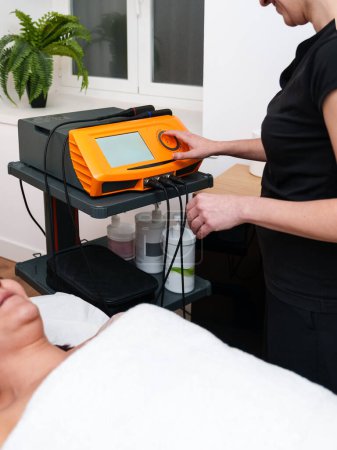 Practicante establece dispositivo de electroterapia para una sesión terapéutica.