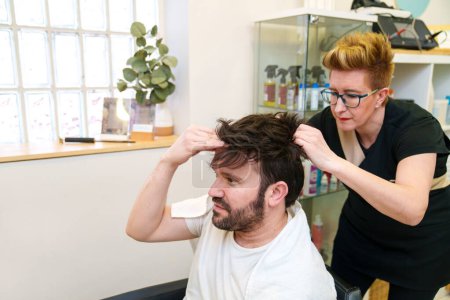 Stylist meticulously adjusts hairpiece for stylish result.