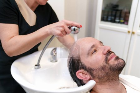 Technicien laver les cheveux du client avant l'application de la prothèse.