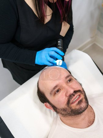 Kliniker führt eine detaillierte Dermaskopanalyse der Kopfhaut des Patienten durch.